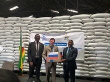 WFP/Adrienne Bolen, Ambassador of the Russian Federation to Zimbabwe, Nikolai V. Krasilnikov hands over a box of wheat procured from Russian funding to Eddie Rowe, WFP Zimbabwe Country Representative & Director and Erasmus Gapara, from Zimbabwe’s Ministry of public service, labour and social welfare.